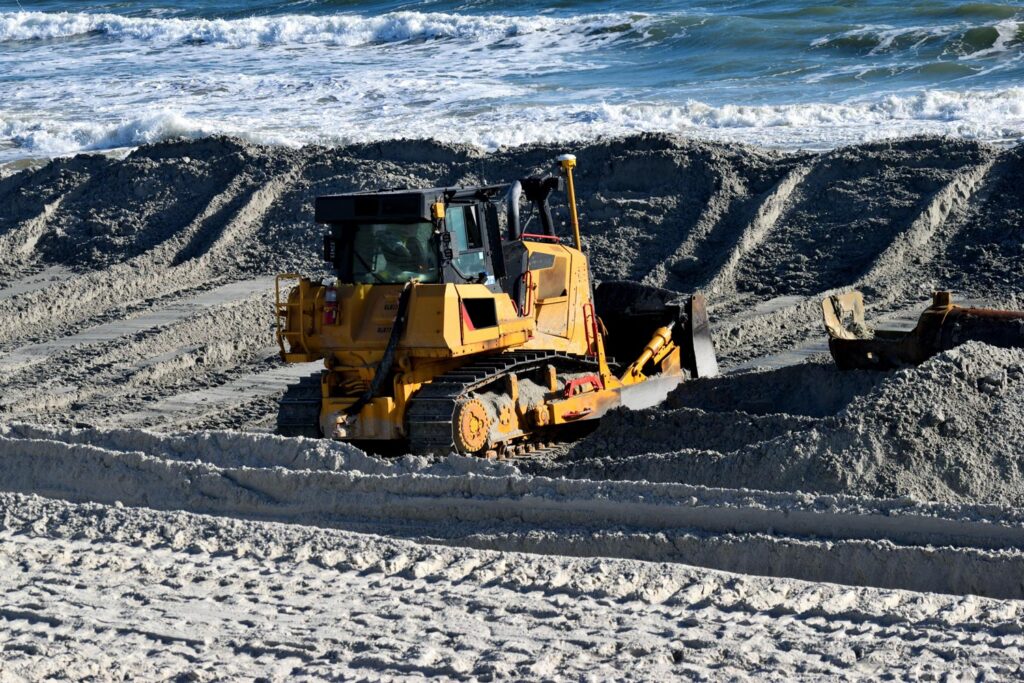 A bulldozer dredging sand on a beach