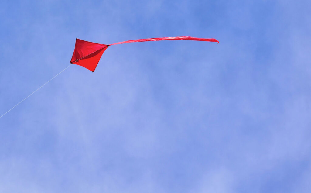A red kite soaring in blue sky.
